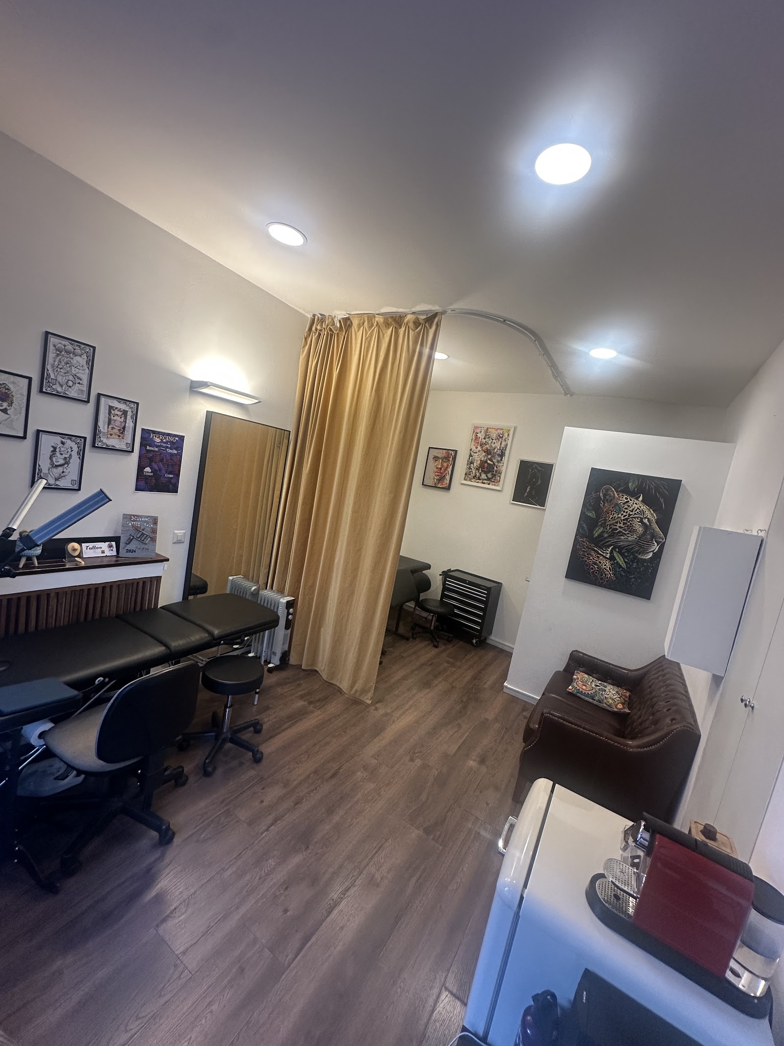 Int&eacute;rieur spacieux du studio avec deux postes de travail, oeuvres d'art aux murs et canap&eacute; en cuir